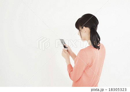 スマートフォンを操作する後ろ姿 女性 の写真素材