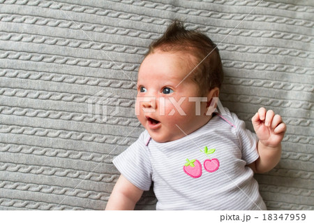 Sweet new born baby in a grey shirt with strawberry picture on a grey knitted blanket Sweet new born baby in a grey shirt with strawberry picture on a grey knitted blanket 18347959