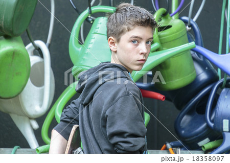 portrait of a teenage boy in front of hanging watering cans portrait of a teenage boy in front of hanging watering cans 18358097