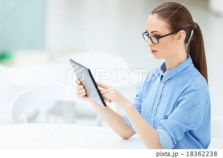 Woman sitting at the desk and using a tablet Woman sitting at the desk and using a tablet 18362238