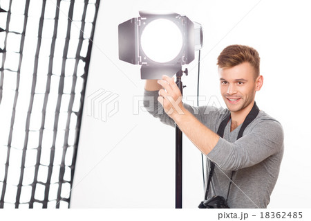 Smiling photographer is busy fixing the spotlight. Smiling photographer is busy fixing the spotlight. 18362485