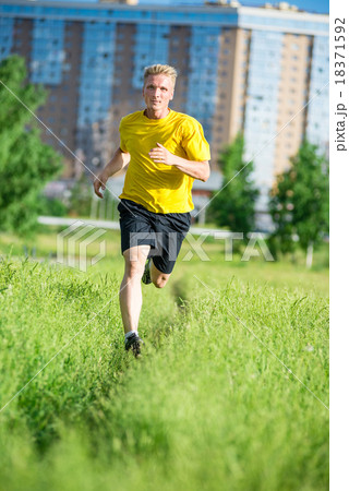 Sporty man jogging in city street park. Outdoor Sporty man jogging in city street park. Outdoor 18371592