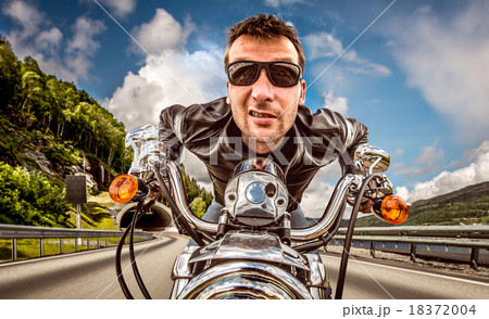 Funny Biker in sunglasses and leather jacket racing on mountain Funny Biker in sunglasses and leather jacket racing on mountain 18372004