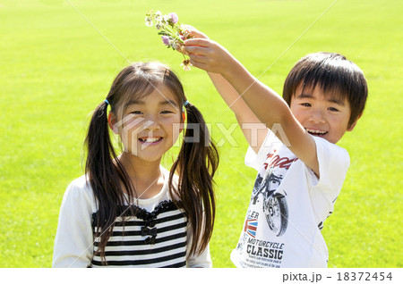 女の子の頭に花の冠を乗せる男の子の写真素材