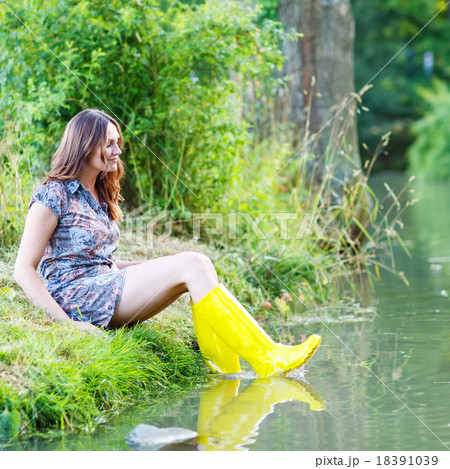 Young beautiful woman sitting in yellow rain rubber boats by a r 18391039