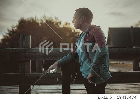 runner standing, relaxing and listening  music 18412474