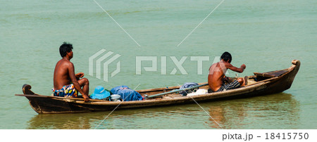 Two Asian men rowing wooden boat on a river 18415750
