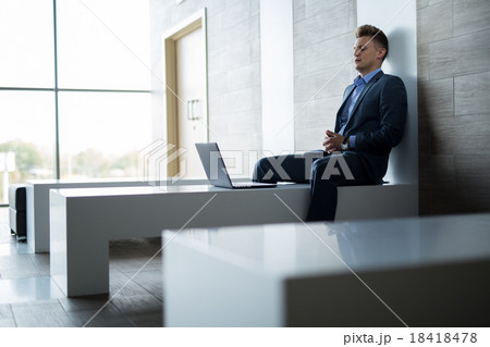 Business man sitting alone on a bench with laptop 18418478