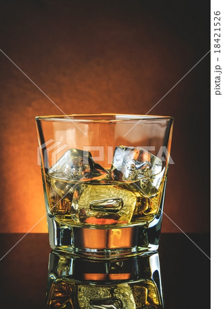 glass of whiskey on black table with reflection, warm atmosphere 18421526