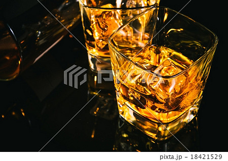 glass of whiskey near bottle on black table with reflection glass of whiskey near bottle on black table with reflection 18421529