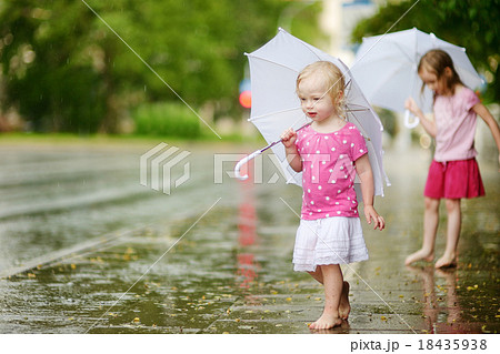 Two cute little sisters having fun under a rain 18435938