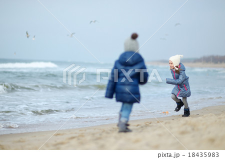 Adorable little girls playing by the ocean Adorable little girls playing by the ocean 18435983