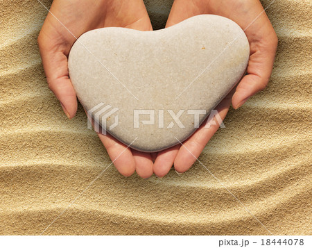 Female hands holding a heart-shaped stone 18444078