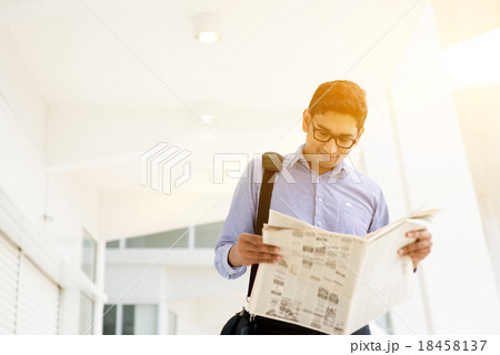 Executive reading newspaper while going to office Executive reading newspaper while going to office 18458137
