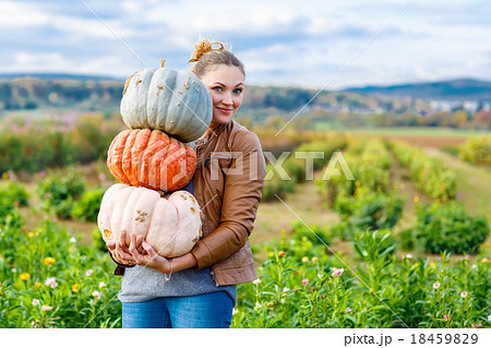 Beautiful woman with three huge pumpkins on farm 18459829