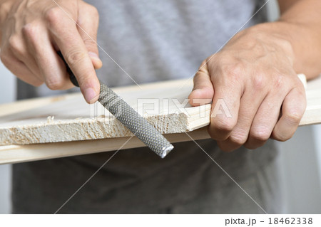 young man filing a wooden board with a rasp 18462338