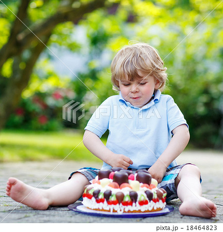 Little boy celebrating his birthday in home's garden with big ca 18464823