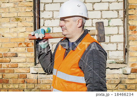 Construction worker with sledgehammer near the bri 18466234