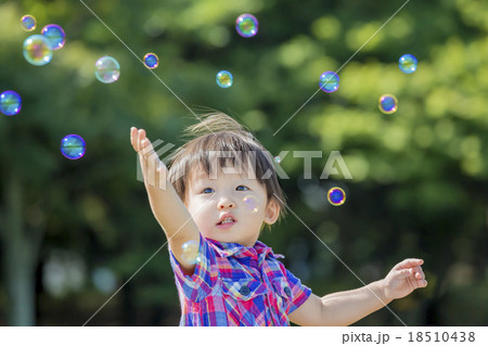 公園でシャボン玉を追う男の子の写真素材