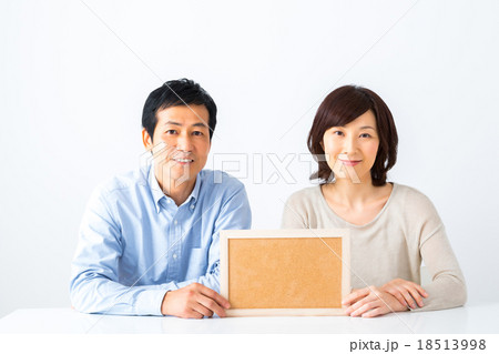 コルクボードを持った夫婦 男性 女性 コピースペース テキストスペース 板 白い背景の写真素材
