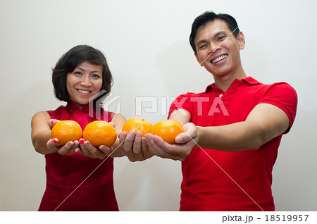 Young couple offering oranges as gold during CNY  18519957