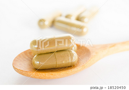 herbal drug capsule on wooden spoon 18520450
