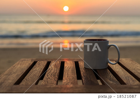 Coffee cup on wood table at sunset or sunrise beach 18521087