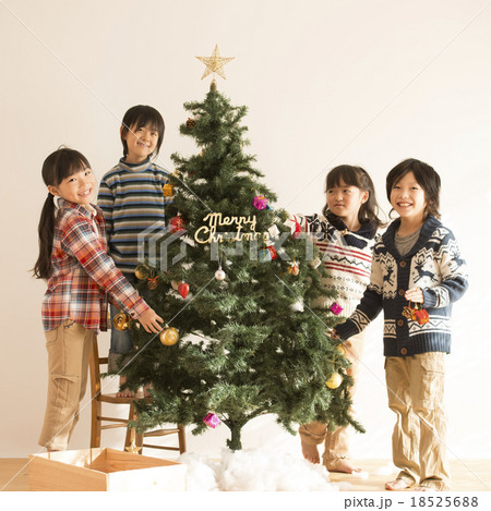 クリスマスツリーの飾り付けをする子供達の写真素材