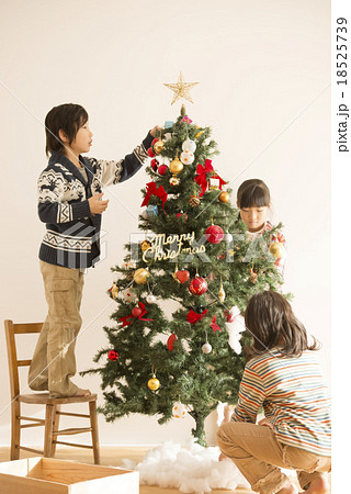 クリスマスツリーの飾り付けをする子供達の写真素材