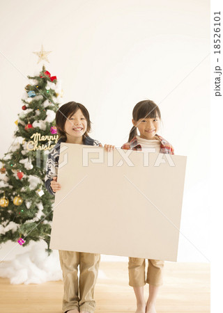 メッセージボードを持つ子供達とクリスマスツリーの写真素材