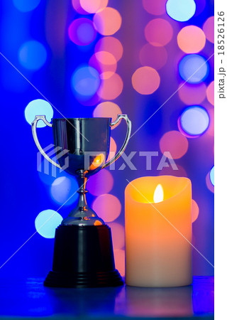 Silver cup trophy and candle against blue bokeh 18526126