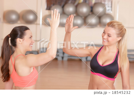 Two girlfriends giving high five in gym  18545232