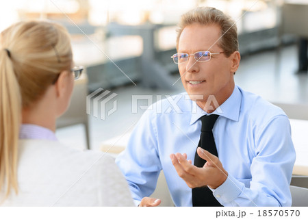 Pleasant businesswoman talking to the colleague  18570570