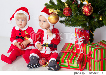 Two children under christmas pine Two children under christmas pine 18580584