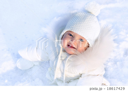 Cute little baby in a white jacket and white hat sitting in fres Cute little baby in a white jacket and white hat sitting in fres 18617429
