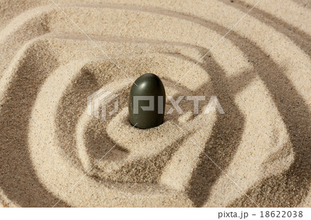 Black stone sticking out of the sand Black stone sticking out of the sand 18622038
