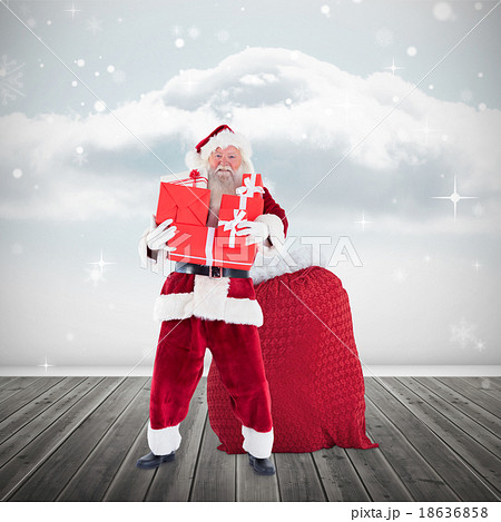 Composite image of santa holding pile of gifts 18636858