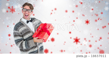 Composite image of happy geeky hipster with wool jacket holding present 18637011