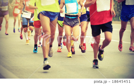 Many marathon runners running on city road 18645451