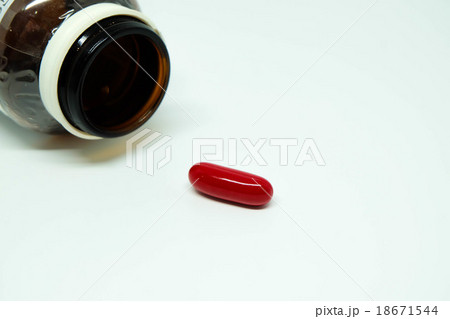 A red pill and a brown glass bottle 18671544