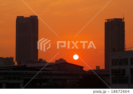 高層ビルの間に沈む夕日 横 の写真素材