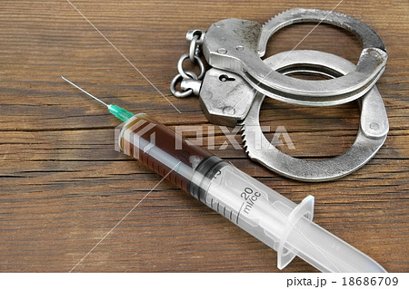 Medical Syringe And Handcuffs On The Wooden Table Medical Syringe And Handcuffs On The Wooden Table 18686709