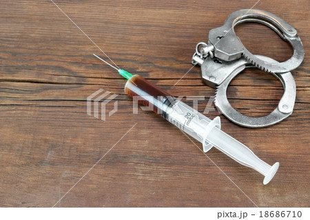 Medical Syringe And Handcuffs On The Wooden Table 18686710