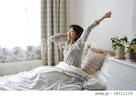 朝ベッドで伸びをする女性の写真素材
