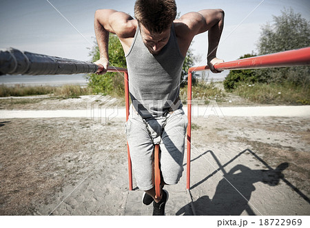 young man exercising on parallel bars outdoors young man exercising on parallel bars outdoors 18722969