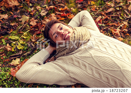 close up of smiling young man lying in autumn park 18723207