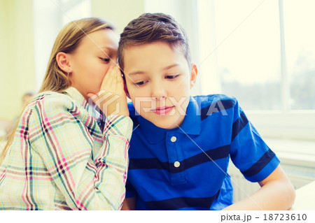 smiling schoolgirl whispering to classmate ear smiling schoolgirl whispering to classmate ear 18723610