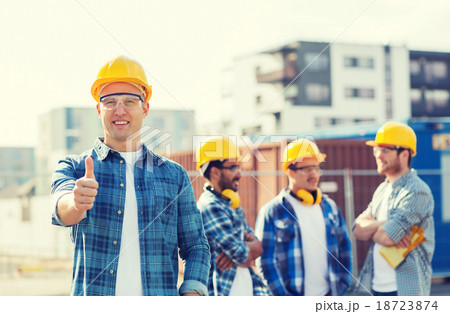 group of smiling builders in hardhats outdoors 18723874