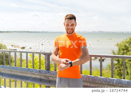 smiling young man with smart wristwatch at seaside smiling young man with smart wristwatch at seaside 18724744