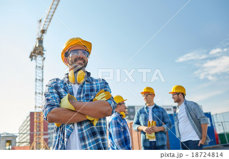 group of smiling builders in hardhats outdoors 18724814